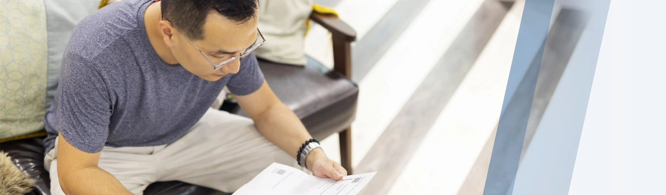 Man on couch looking over paperwork