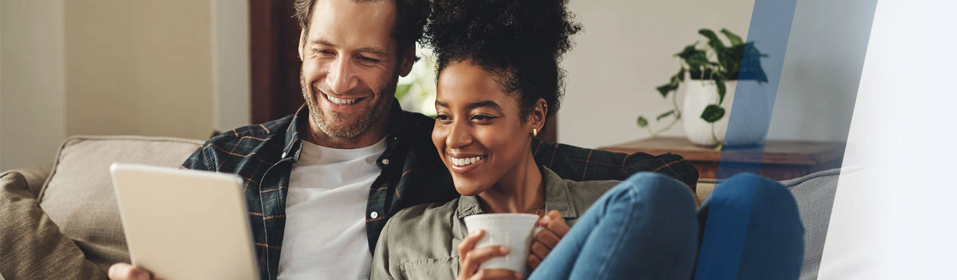 Smiling couple looking at tablet on couch