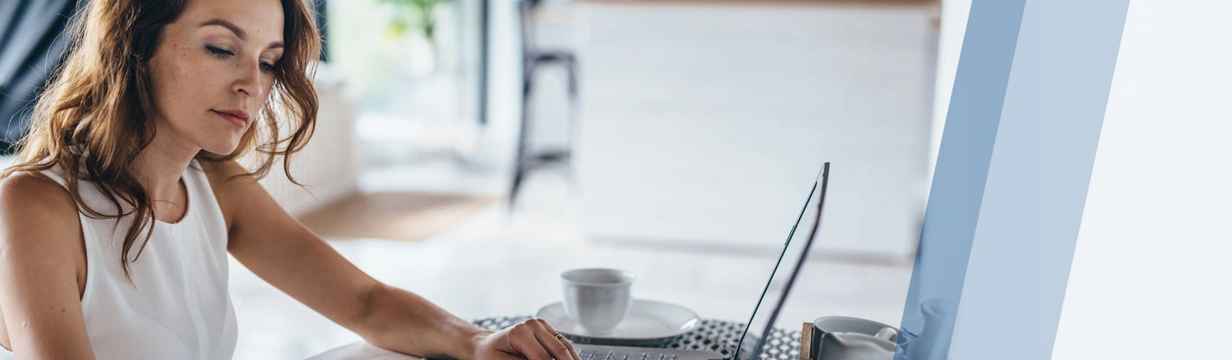 woman reading documents while typing on a laptop